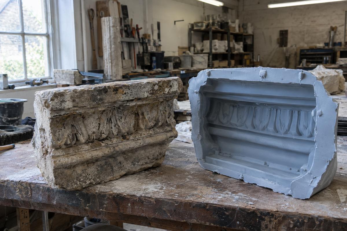 Historic stone fragment beside a silicone mould capturing its worn detail