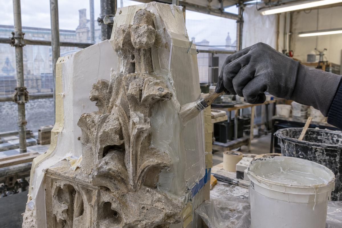 Gloved hands applying layered brush-on silicone to carved stone detail