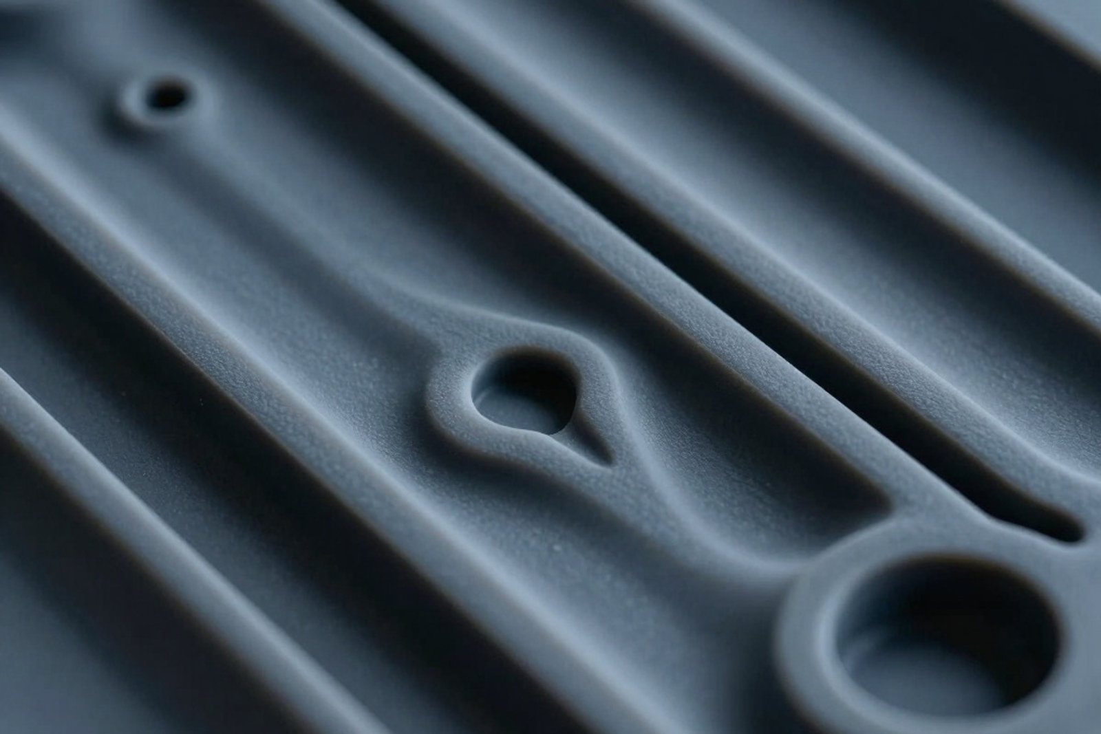 Close view of a grey moulded silicone part with crisp ribs and a moulded through-hole taken straight from the tool